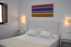 een slaapkamer met een wit bed en 2 witte kussens bij Hostal Doña Lola Marina in Zahara de los Atunes
