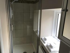 a shower with a glass door next to a window at Garron House in Auchterarder