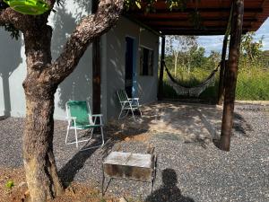 a house with two chairs and a hammock next to a tree at Loft com vista para as montanhas in Chapada dos Guimarães