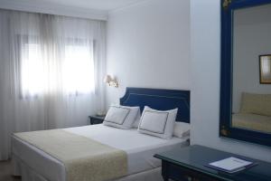 1 dormitorio con cama con espejo y ventana en Hospederia Doña Lola Zahara en Zahara de los Atunes