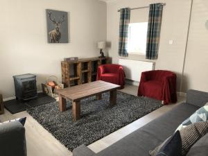 a living room with a table and two red chairs at Garron House in Auchterarder