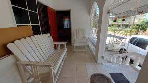 a porch with two white chairs on a balcony at Charming 1-Bedroom House in St Thomas Jamaica in Belfast