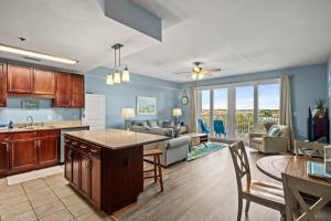 a kitchen and living room with a couch and a table at White Sandy Beaches, Sunsets & Seashells at Laketown Wharf #402 by Nautical Properties in Panama City Beach