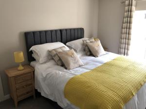 Una cama con manta amarilla y almohadas. en Garron House en Auchterarder