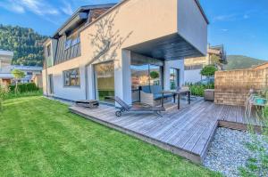 a backyard with a wooden deck with a table and chairs at Gletscherblick 1 - by Alpen Apartments in Zell am See