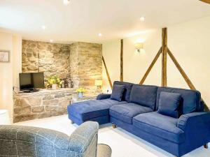 una sala de estar con sofás azules y una pared de piedra. en Kite 1 - Uk6549, en Llanfihangel-Bryn-Pabuan