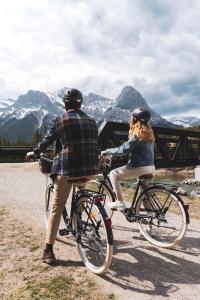 un hombre y una mujer montando bicicletas delante de las montañas en Canmore Rocky Mountain Inn en Canmore