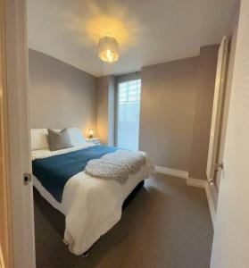 a bedroom with a bed with a blue blanket and a window at City Apartment with Terrace in Leicester