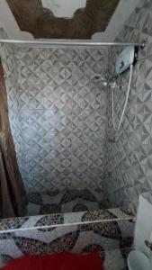 y baño con ducha y pared de azulejos. en Lovely 2 Bedroom House in St Thomas Jamaica, en Belfast