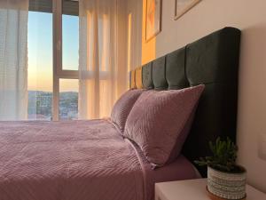 a bedroom with a large bed with a large window at Comfy Nest Apartment- free parking in Tirana