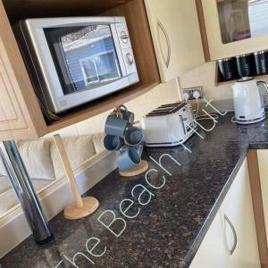 a kitchen counter with a microwave and a toaster at The Beach Hut on Lyons Winkups Holiday Park in Kinmel Bay