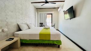 1 dormitorio con 1 cama y TV en la pared en Hotel MAYARI Holbox en Holbox Island