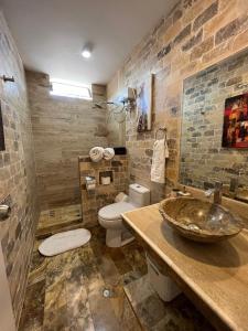 a bathroom with a sink and a toilet and a stone wall at Casa Villa Victoria en Pisco in Pisco