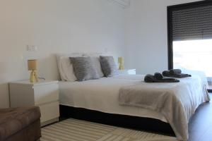 een witte slaapkamer met een groot bed met een raam bij Apartamento Flow Living, com piscina, em Olhão in Olhão +30 foto's