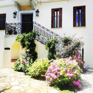 a white building with flowers in front of it at Archontiko Polyzos in Portaria