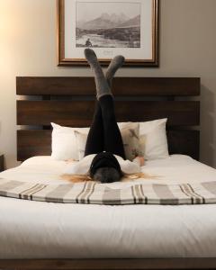 een persoon die op een bed ligt met zijn benen in de lucht bij Canmore Rocky Mountain Inn in Canmore