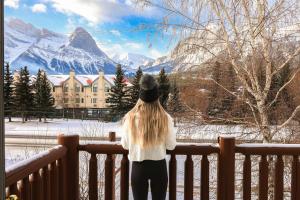 een vrouw die op een hek staat en naar de bergen kijkt bij Canmore Rocky Mountain Inn in Canmore