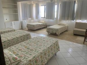 a room with three beds and a chair and a couch at Beira Mar in Salvador