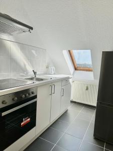 a kitchen with white cabinets and a sink and a window at Ferienwohnung Flaming House Bitterfeld in Bitterfeld