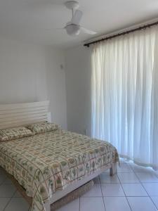 een slaapkamer met een bed en witte gordijnen bij Beira Mar in Salvador