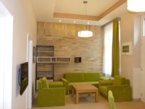 a living room with green furniture and a brick wall at Soleil Apartman Szeged in Szeged