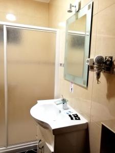 a bathroom with a sink and a shower with a mirror at Hostel Boutique Marisol in Monte Gordo