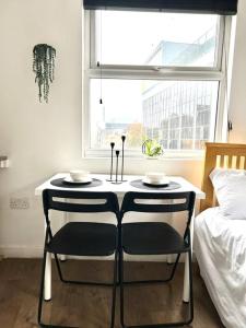 a table with two chairs in a bedroom with a window at Very Nice Studio Flat in a Great Location in London