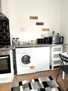 a kitchen with a washing machine and a microwave at Very Nice Studio Flat in a Great Location in London