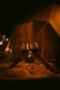 a person is holding two glasses of wine at Domo Pajcha, Samaipata Glamping in Samaipata