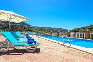 eine Reihe von Stühlen und ein Sonnenschirm neben einem Pool in der Unterkunft Casa Los Cortijillos in Alcaucín
