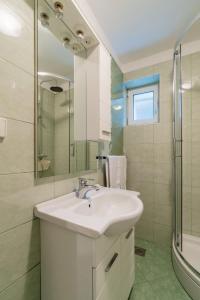 Un baño blanco con lavabo y ducha. en Apartman Linnea, en Rijeka 7 fotos más