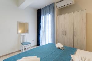 a bedroom with a blue bed and a window at White Pearl Apartments in Paralia Katerinis