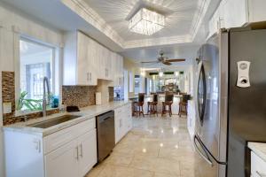 a kitchen with white cabinets and a stainless steel refrigerator at Waterfront Home with Game Room, 2 Miles to Beach! in Seminole