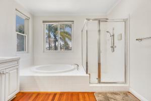a white bathroom with a tub and a shower at A Stunning Beach villa Walking to Huntington Beach in Huntington Beach