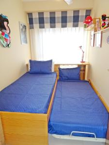 dwa łóżka w sypialni z niebieską pościelą i oknem w obiekcie AQUARIUM playa de Gandía - ( Alquiler solo familias ) w mieście Playa de Gandia