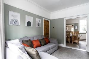a living room with a gray couch with orange pillows at Merton House - Entire Modern City Centre Home in Leicester