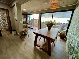 a living room with a wooden table and large windows at Victoria Ocean View Room in Ponta do Pargo