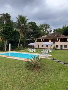 una piscina con sedie e ombrelloni di fronte a una casa di Sítio dos Guedes a Guapimirim