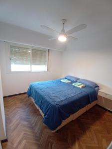 1 dormitorio con 1 cama azul y ventilador de techo en Departamento en el centro de Rosario en Rosario