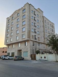 een groot stenen gebouw met auto's geparkeerd voor het bij هومينج - Homing (شقق مفروشة) in Salalah