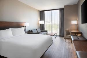 a hotel room with a large white bed and a chair at AC Hotel by Marriott Pittsburgh Downtown in Pittsburgh