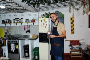 Un hombre con un delantal parado junto a un refrigerador. en Hostal Macondo Bogotá en Bogotá