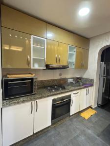 uma cozinha com armários brancos e electrodomésticos de aço inoxidável em Résidence Galets Sur Mer em Dar Bouazza