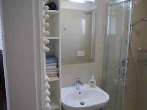 a white bathroom with a sink and a shower at Apartment Romana in Opatija