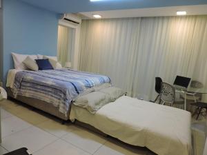 Schlafzimmer mit einem Bett und einem Tisch mit einem Laptop in der Unterkunft Edf Time Ponta Verde, Studio 523 in Maceió