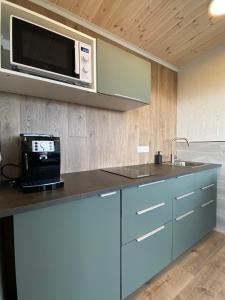 uma cozinha com um balcão com um micro-ondas e um lavatório em Brekkukot Cottages, Blönduós em Blönduós
