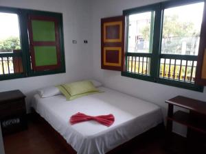 Un dormitorio con una cama blanca con una pajarita. en Hostal Casa de Los Taitas en Salento