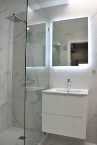 ein weißes Bad mit einem Waschbecken und einer Dusche in der Unterkunft Amazing 2-Bedroom Townhouse near Eagle Beach in Palm-Eagle Beach