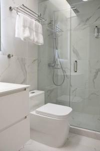 ein weißes Bad mit einem WC und einer Dusche in der Unterkunft Amazing 2-Bedroom Townhouse near Eagle Beach in Palm-Eagle Beach