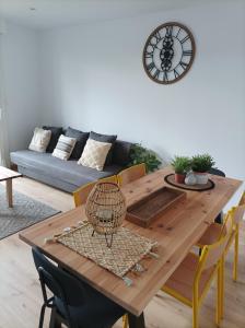 een eettafel met stoelen en een klok aan de muur bij Sweet Home in Mulhouse